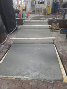 Fresh concrete being poured and leveled for an industrial concrete ramp